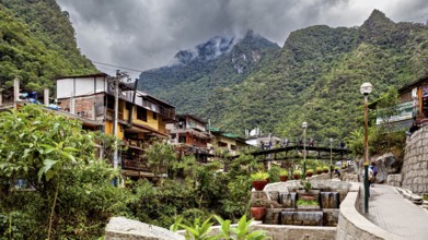 Small village surrounded by mountains under cloudy skies with lush vegetation, The city in the