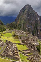 Historic ruins and a dramatic mountain against a cloudy sky, The ruins of the Inca city of Machu