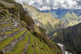 Green terraces over a river landscape under dramatic clouds, The ruins of the Inca city of Machu