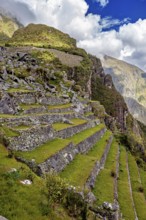 Terraces with rocky rocks and mountain formations surrounded by green and cloud-covered skies, The