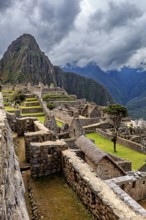 View of the ruined city of Machu Picchu with surrounding Andes and cloudy sky, The ruins of the