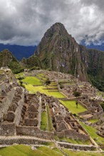 Aerial view of Machu Picchu ruins and mountainous landscape under cloudy sky, The ruins of the Inca