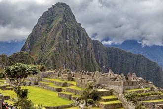 Majestic mountain behind ancient ruins under thick grass and clouds, The ruins of the Inca city of