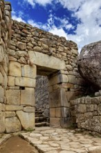 Inca stone archway with blue sky and some clouds, The ruins of the Inca city of Machu Picchu in