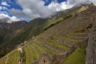 Wide view of stone terraces on a mountainside under clouds, The ruins of the Inca city of Machu