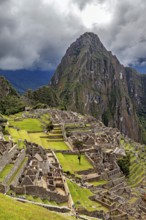 View of historic ruins and a mountain peak under a dramatic sky, The ruins of the Inca city of