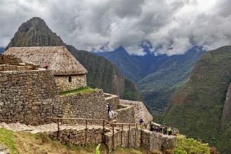 Historic ruins with grass-covered huts in the Andes against a cloudy sky, The ruins of the Inca