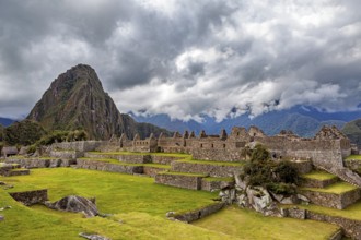 Impressive ruins of Machu Picchu with a distinctive mountain in the background and dramatic clouds,