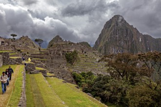 Walkers explore the ruins of Machu Picchu in front of dramatic mountain scenery, The ruins of the