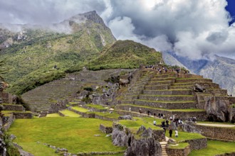Stepped terraces with ruins against a dramatic mountain backdrop full of clouds, The ruins of the