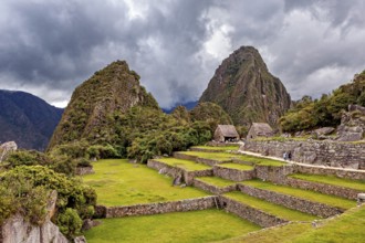 Green terraces and ruins against a dramatic, cloud-covered background, the ruins of the Inca city