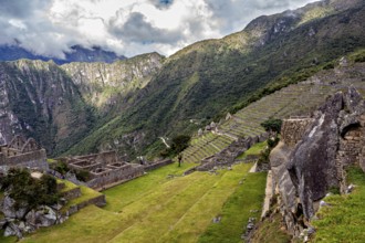 Descending terraces of ruins against mountain backdrop and cloudy sky, The ruins of the Inca city