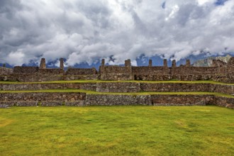 Plain with ancient stone ruins and grassy surfaces under a cloudy sky, The ruins of the Inca city