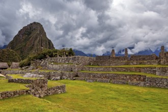 Ancient ruins against a dramatic sky with dark clouds and green areas, The ruins of the Inca city
