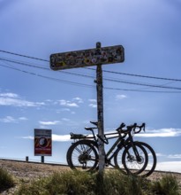 Sticker-covered sign with bicycles and surfboards, Nazaré, Portugal