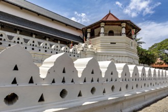 A temple with a white wall and a red roof under a clear sky, The Temple of the Tooth in Kandy Sri