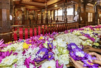 Colourful floral arrangements on an altar in a richly decorated wooden building, people and