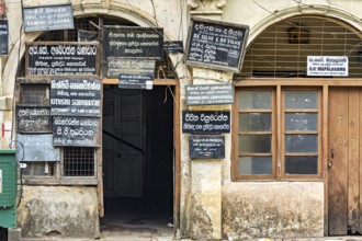 Old façade of a building with numerous colorful signs and wooden windows in colonial style, door