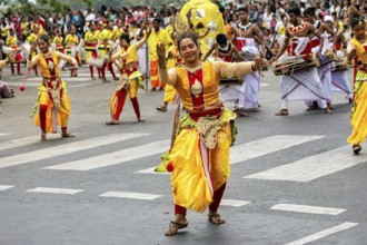 Woman in glowing traditional costume dances joyfully at a cultural parade, The Perahera Parade in