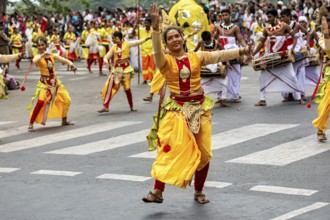 Dancers in colorful, traditional Indian costumes during a lively parade at a crossroads, The