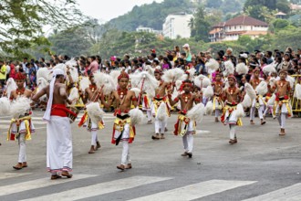 Children in festive dance costumes move happily through the streets, watched by spectators, The