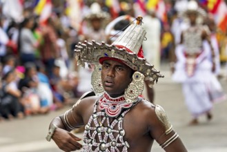 Close-up of a man wearing an elaborate, traditional headdress at a parade, The Perahera Parade in