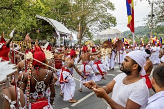 Dancers in moving costumes with flags and drums at a street festival, The Perahera Parade in Kandy