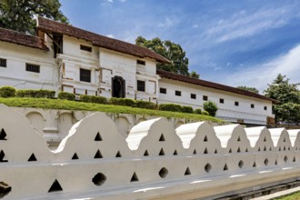 Historic temple with white stone wall, red roof and clear sky, The Temple of the Tooth in Kandy Sri
