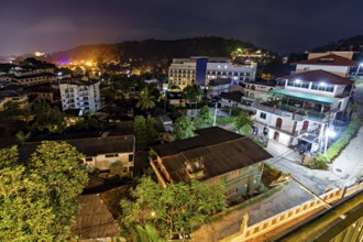 Nighttime city view with illuminated buildings and tropical trees creating a warm and inviting