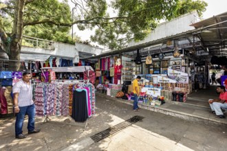 Market under trees, stalls selling clothes, relaxed market atmosphere, dealers in the market halls