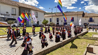 People in a colorful parade with rainbow flags walk along under a sunny sky, traditional parade of
