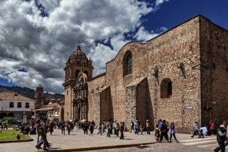 Classic church structure with a passing crowd against a dramatic cloudy sky, The churches of Cusco