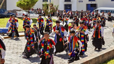 Children and adults in traditional garments move in a colorful procession on the street,