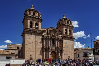 Impressive cathedral with decorated towers surrounded by a lively crowd and a clear sky, The