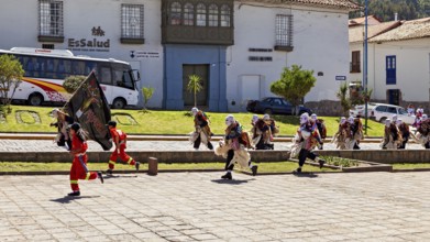 Walking people in masks and costumes cross a paved street, traditional parade of festival groups in