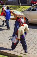 Person with traditional robe and colorful headdress on a street, traditional parade of festival