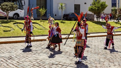 Dancers in colorful costumes with feather headdress perform a traditional performance on the