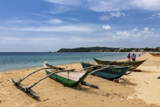 Beach backdrop with green fishing boats in the sand, clear turquoise water and blue sky,