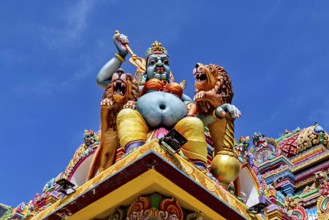 Colourful sculpture of a mythological being with lions on a temple against a blue sky, The Sri