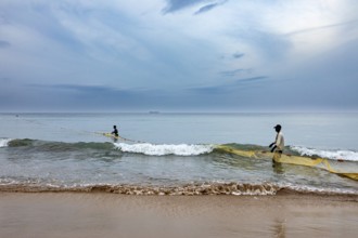 Two fishermen in the sea pull a net across the waves, calm coastal atmosphere, traditional