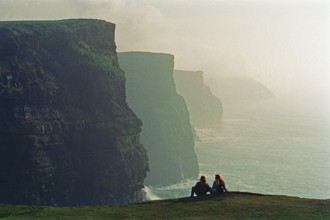 People on the edge of a cliff, there was no fence back then, Cliffs of Moher, County Clare,