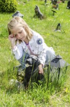 Grieving blonde 7-year-old girl at her dog's grave at pet cemetery in Ystad, Skåne County, Sweden,