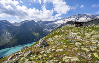 Mountain hut Bergseehütte with Swiss flag in picturesque mountain landscape, view of Damma Glacier
