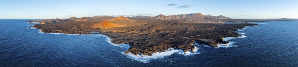 Coast with lava fields, volcanic landscape near Los Hervideros with red volcano Montaña Bermeja, in