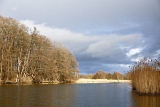 Spring atmosphere with cloudy skies and sunshine over a quiet river, Peenetal nature park Park,