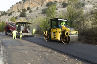 Asphalt road construction team of workers resurfacing tarmac in rural area, near Albarracin, Teruel