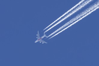 Airbus A380 jet passenger aircraft of Emirates airlines flying in a blue sky with contrails or