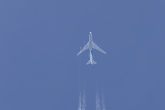 Boeing 747 jumbo jet cargo aircraft flying in a blue sky with contrails or vapour trails behind,