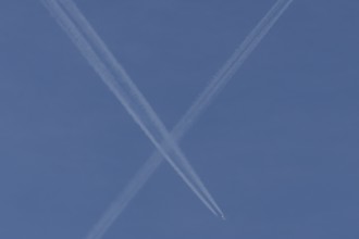 Aircraft contrails or vapour trails crossing in a blue sky, England, United Kingdom