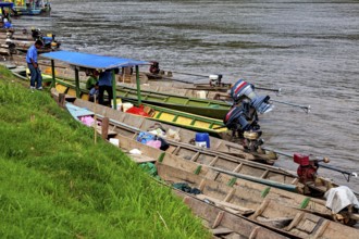 Wooden boats with motors on the banks of a river with grassy banks, longboat on a river near